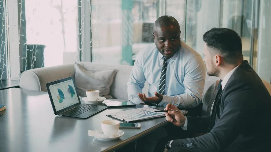 Two business professionals analyzing market trends on digital devices in an office setting.